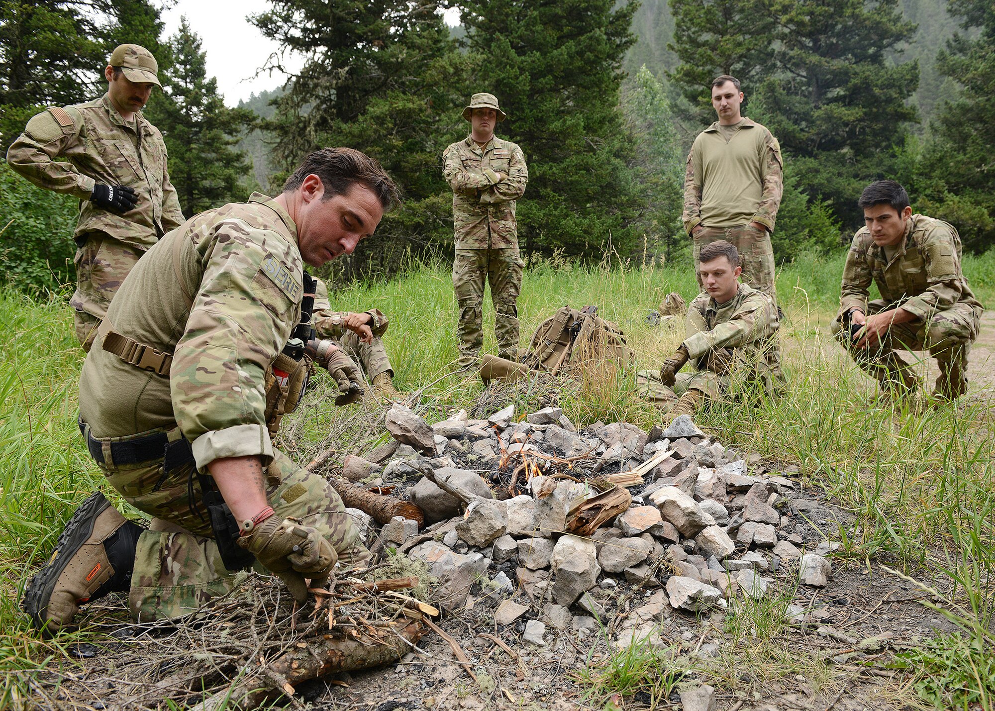 A group of 6 men surround a campfire.