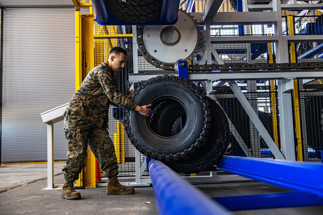 U.S. Marine Corps Lance Cpl. Mustafa Siddiqi, an inventory management specialist with 2nd Supply Battalion, 2nd Marine Logistics Group lifts a tire off of the new tire carousel on Camp Lejeune, North Carolina, Nov. 29, 2022. 2nd Supply Battalion incorporated this new tire carousel to provide responsive ground equipment inventory control and integrated operational-level logistics capabilities in order to maximize II Marine Expeditionary Force material readiness and sustainment. (U.S. Marine Corps photo by Cpl. Meshaq Hylton)