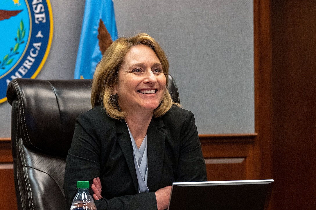 Deputy Defense Secretary Kathleen H. Hicks sits smiling at a desk.