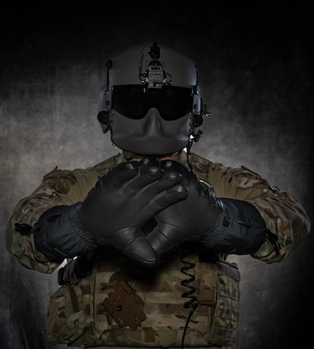 U.S. Air Force Staff Sgt. Dylan Metcalf, a 54th Helicopter Squadron flight engineer, poses with a pair of heated glove prototypes being tested by Team Minot at Minot Air Force Base, North Dakota, July 28, 2023. The 54th HS can work up to approximately 10,000 feet where temperatures can be extremely low, requiring the highest level of cold weather equipment to stay warm and offset hypothermia. (U.S. Air Force photo by Airman 1st Class Alexander Nottingham)