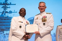 Fleet Command Master Chief Huben Phillips receives an award from Vice Adm. Daniel Dwyer, commander, U.S. 2nd Fleet, during his retirement ceremony, Aug. 11, 2023.