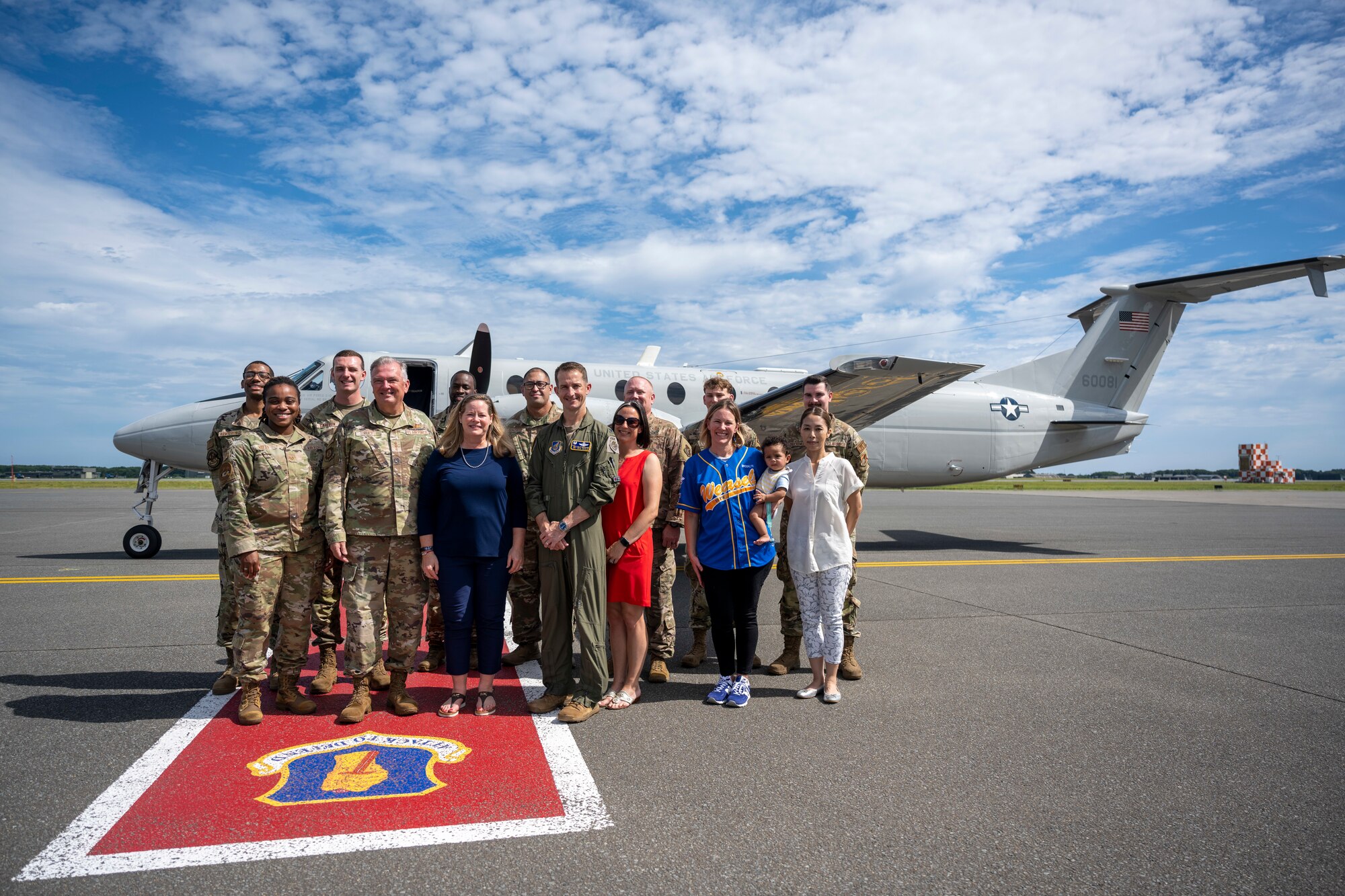 Group of people pose for a photo on a flightline.