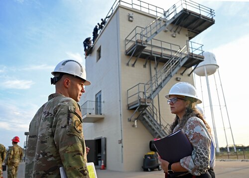 U.S. Air Force Lt. Col. Branden Delong, 312th Training Squadron commander, and Dr. Wendy Walsh, Air Education and Training Command chief learning officer, discuss the repelling course at the Louis F. Garland Department of Defense Fire Academy, Goodfellow Air Force Base, Texas, Aug. 8, 2023. The repelling follow-on course teaches students how to save people from steep cliffs, tall buildings, and waterways. (U.S. Air Force photo by Senior Airman Sarah Williams)