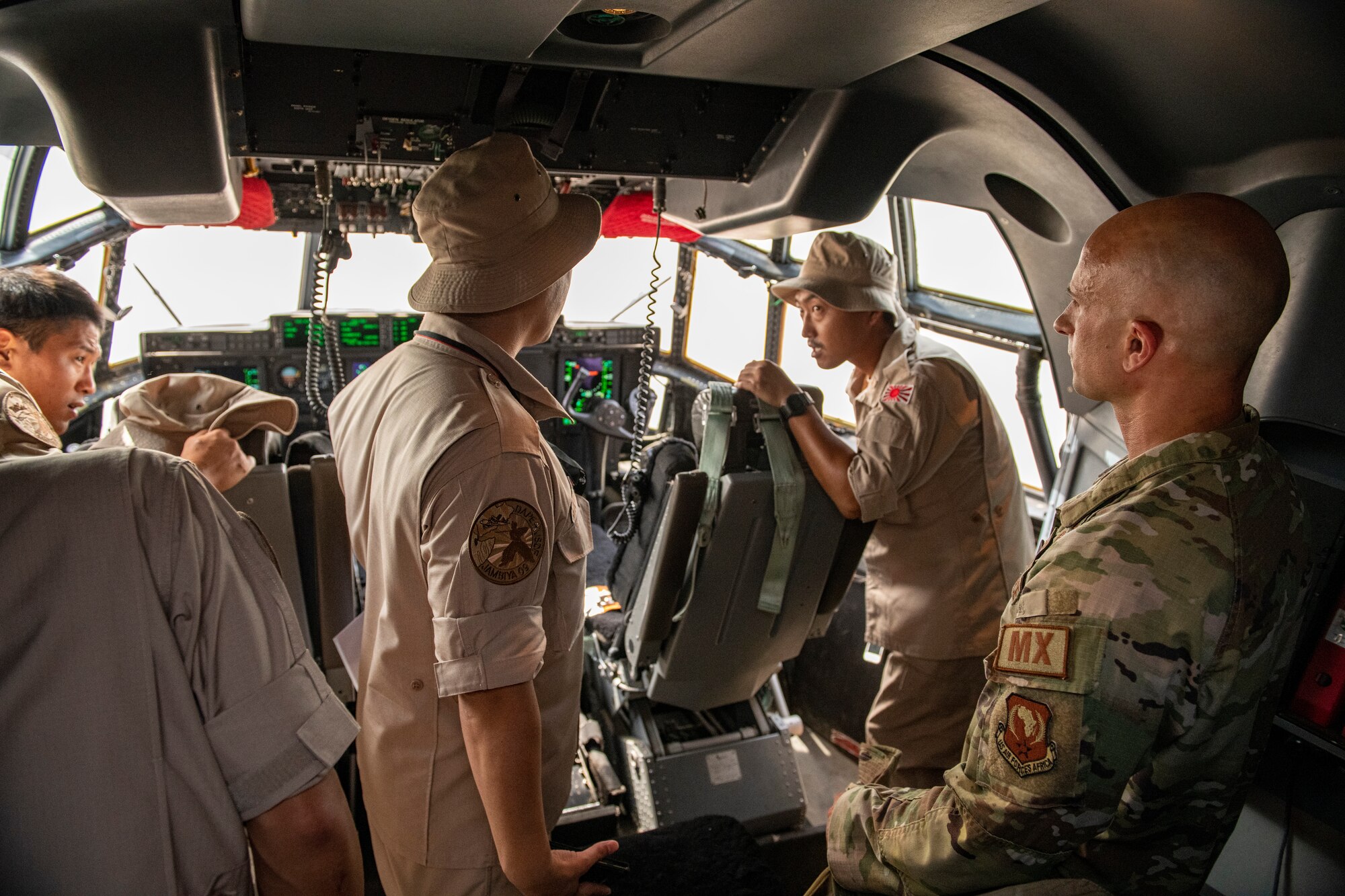 Photo of service members speaking in the cockpit of a cargo plane