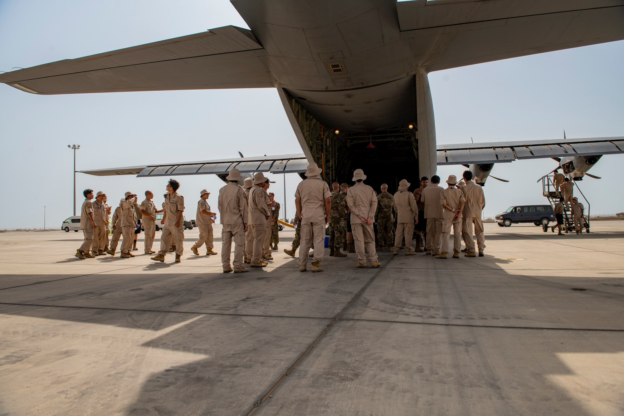 Photo of service members standing behind a cargo plane