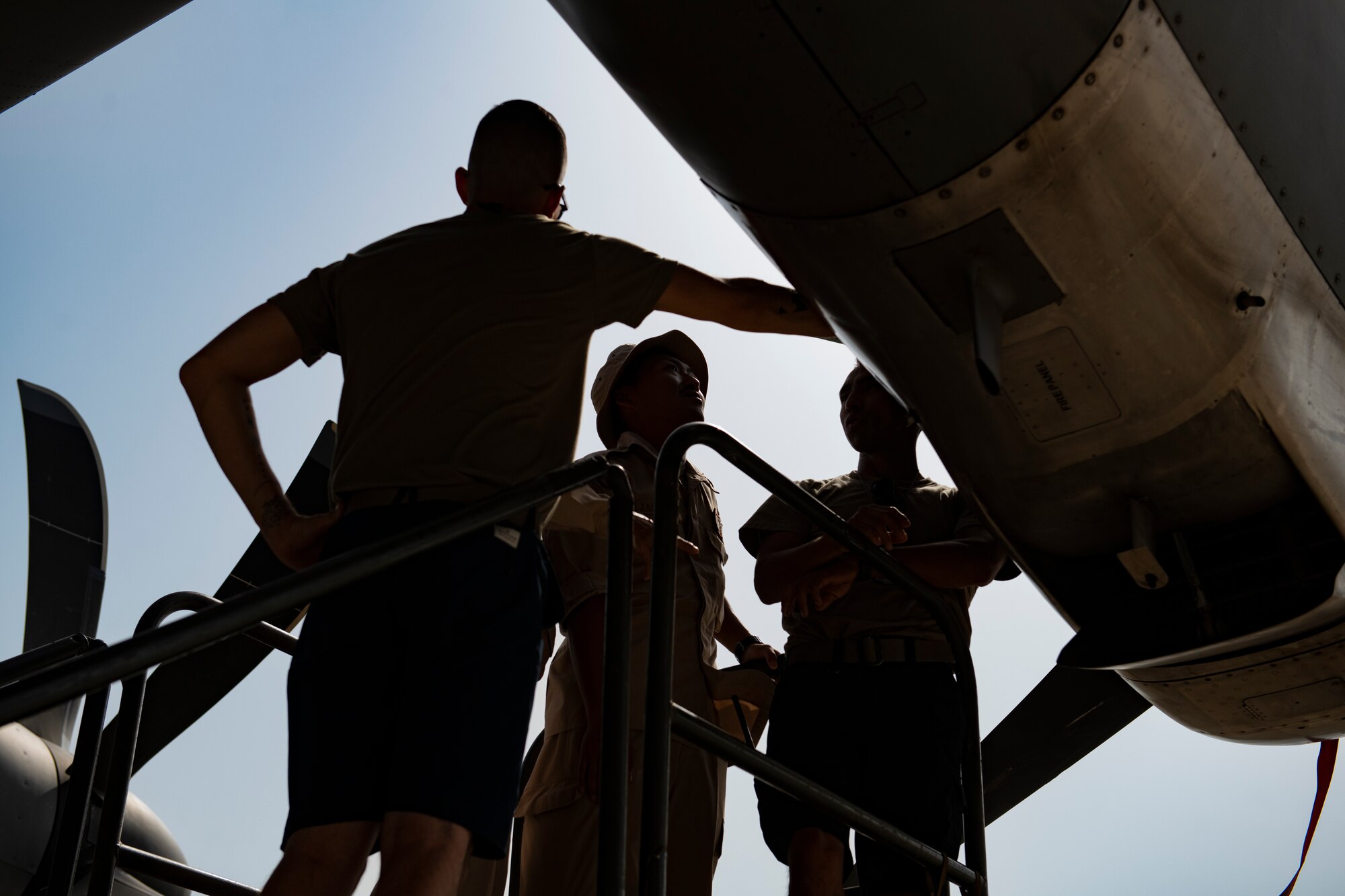 Photo of three men standing next to an airplane engine