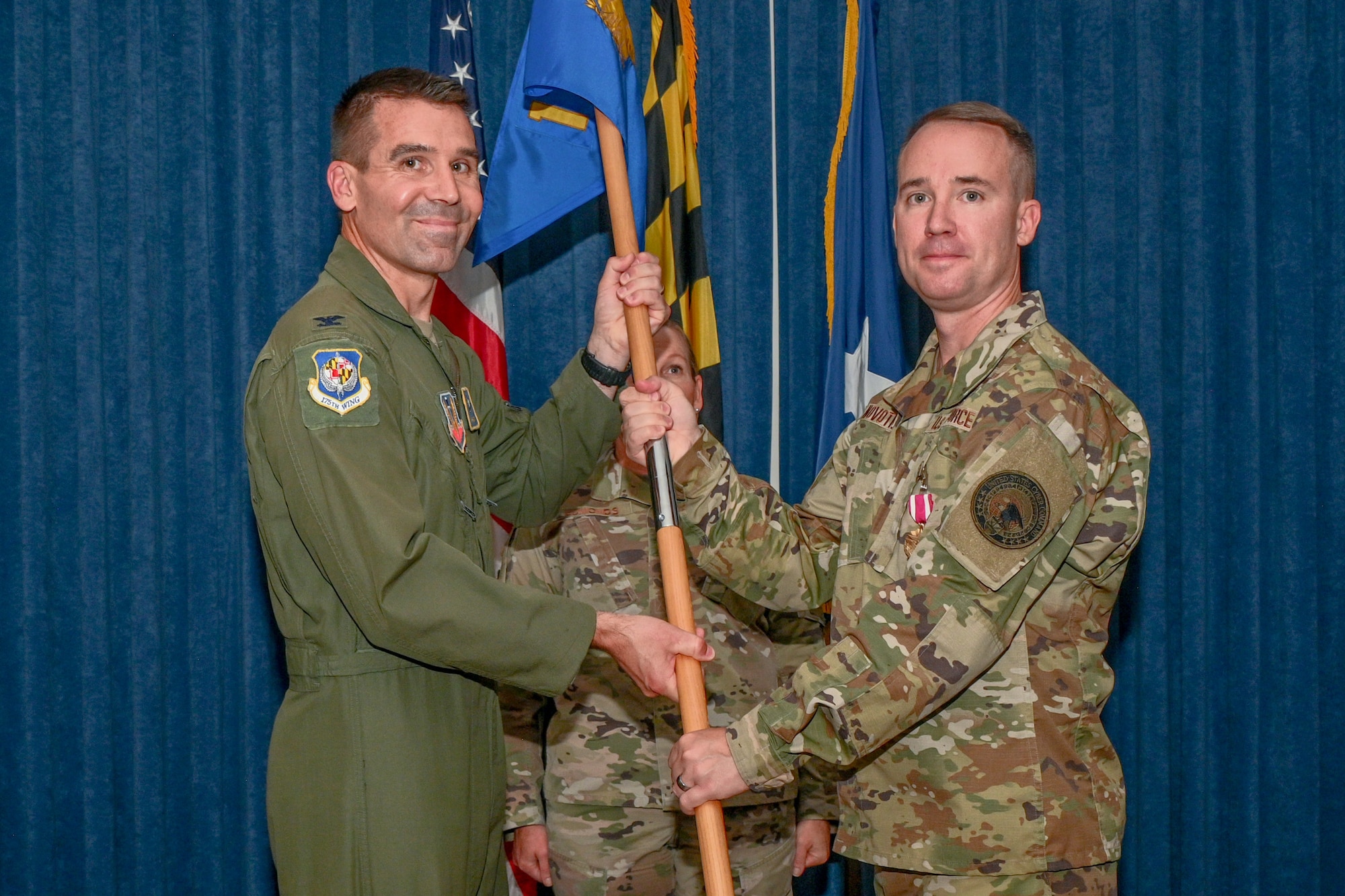 U.S. Air Force Brig. Gen. Reid Novotny, right, 175th Cyberspace Operations Group outgoing commander, passes the guidon to Col. Richard Hunt, left, 175th Wing commander, during the 175th COG change of command ceremony, August 12, 2023, at Martin State Air National Guard Base, Maryland.