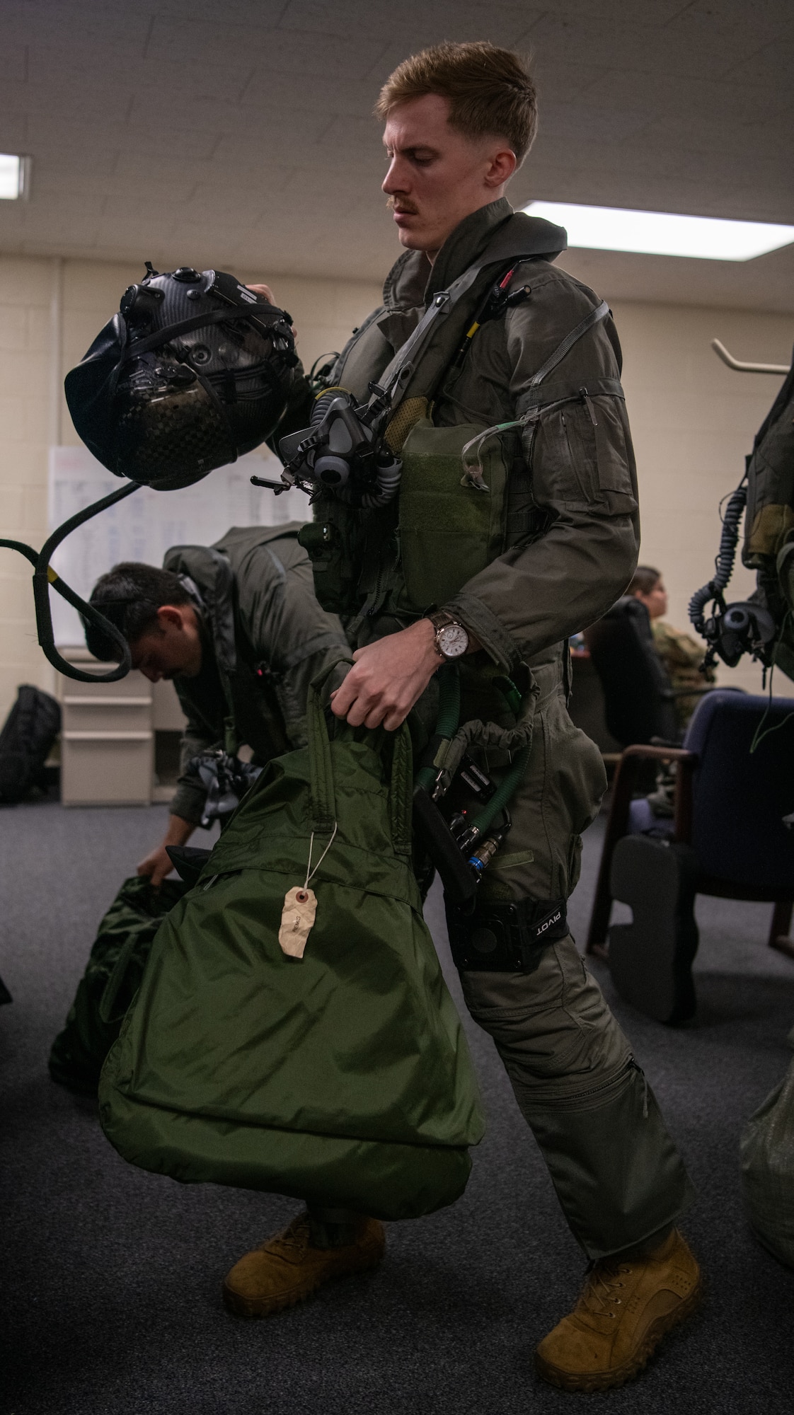 A pilot holds a bag and helmet while conducting pre-flight preparations.