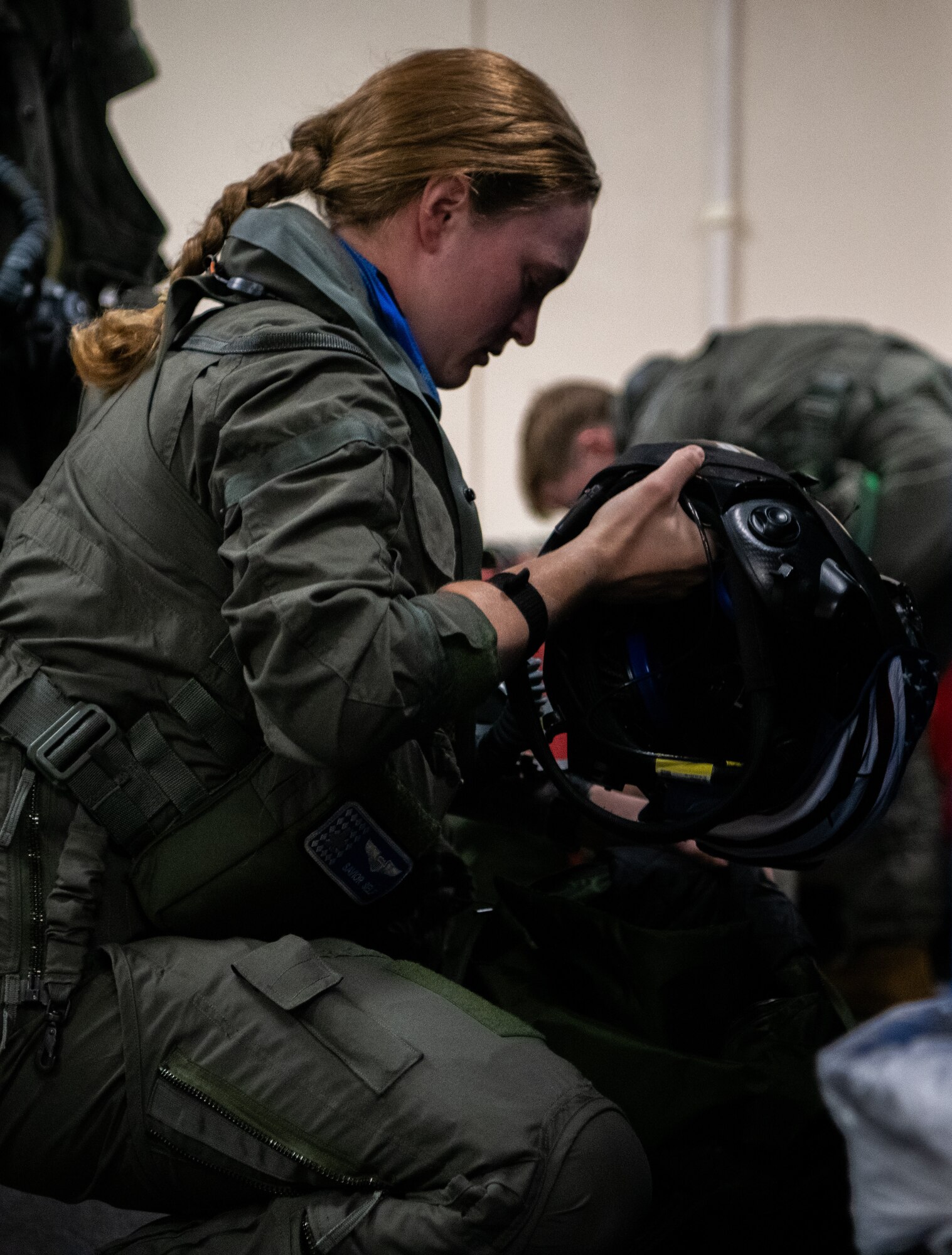 A pilot holds a helmet while conducting pre-flight preparations.