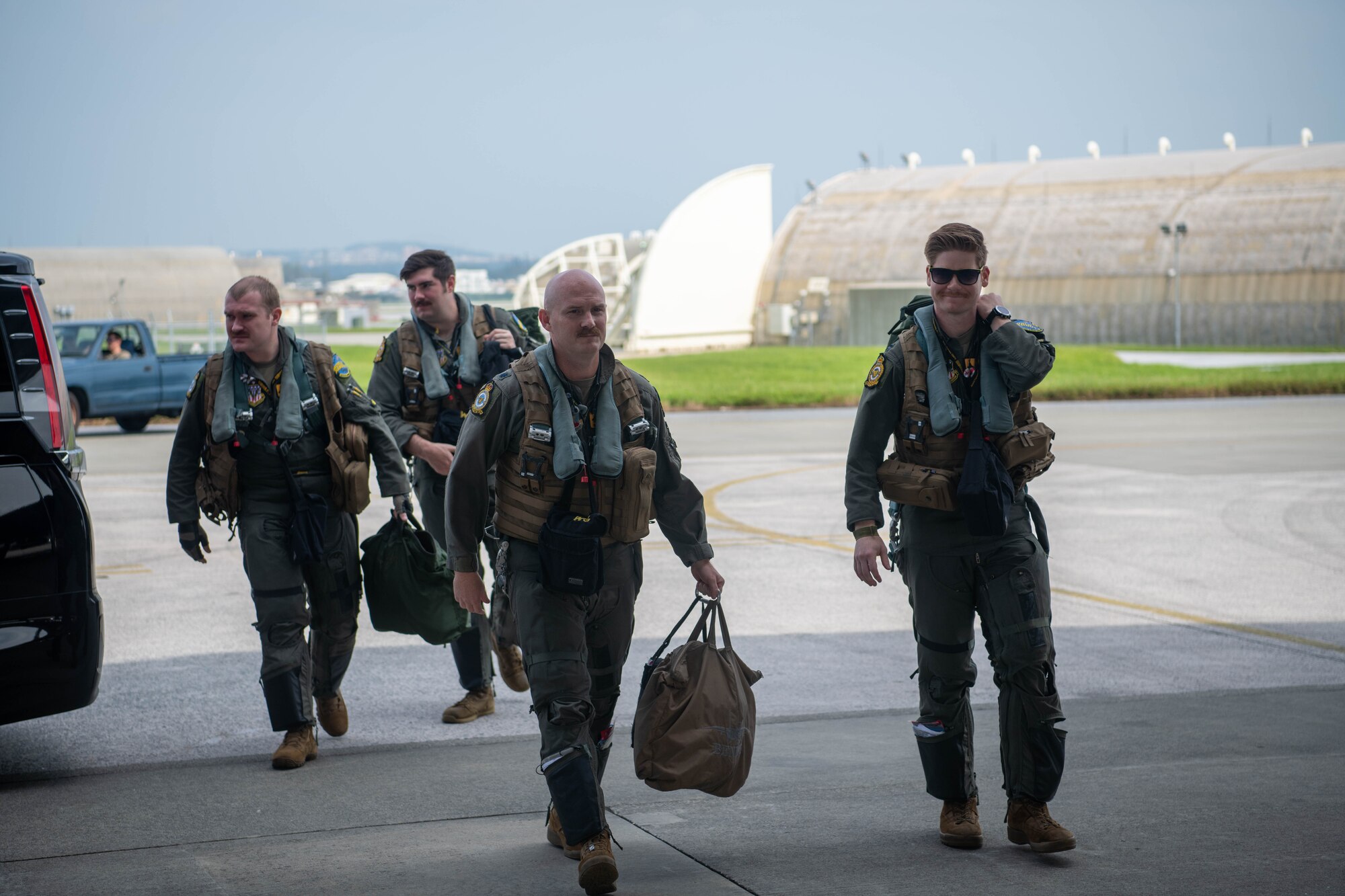 Four pilots carrying bags walk in a direction.