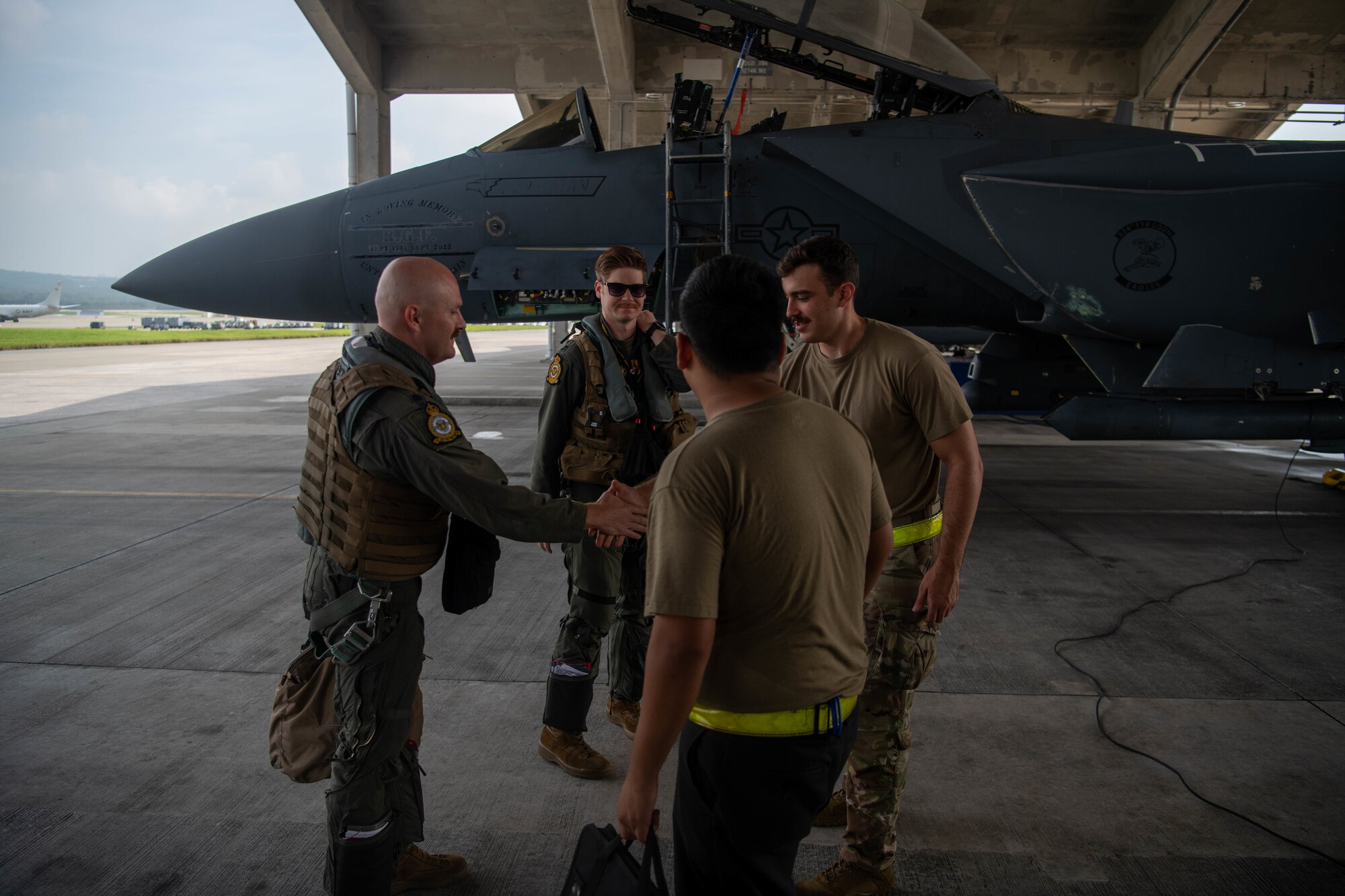 Two pilots and two maintenance workers greet each other in front of an F-15E Strike Eagle.