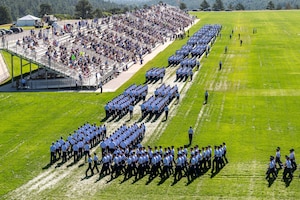 Air Force Academy cadets take part in a parade on a large field.
