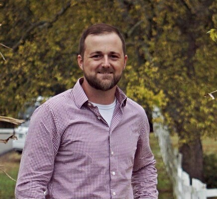 Man stands in front of trees smiling