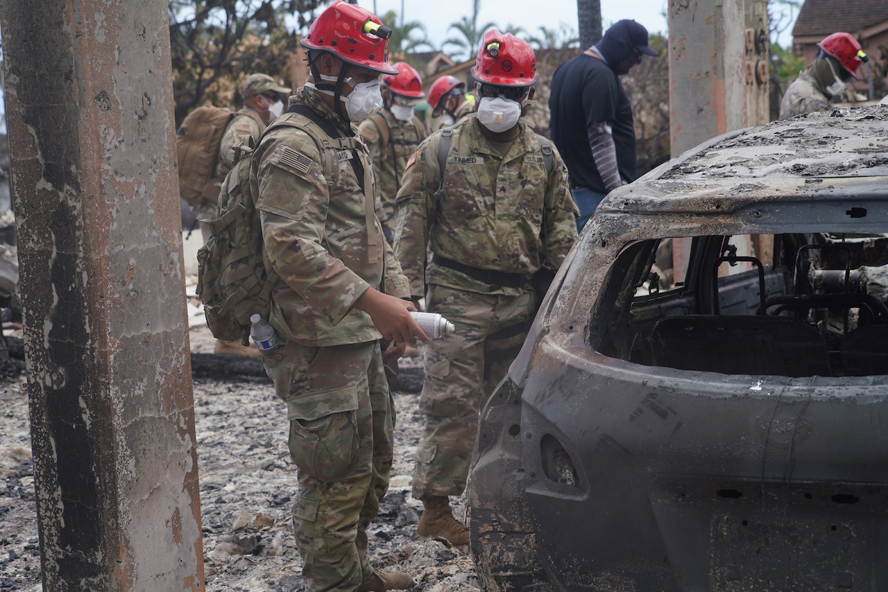 National Guard and local officials assess wildfire damage to a car in Maui, Hawaii.