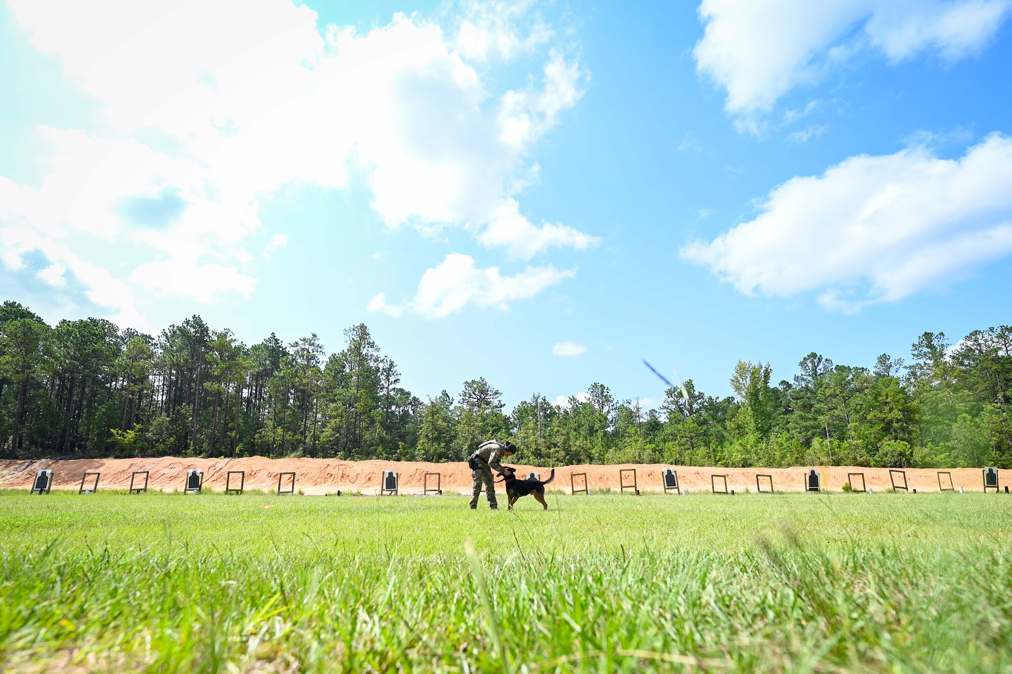 A soldier rewards her dog for a successful response on the firing range.