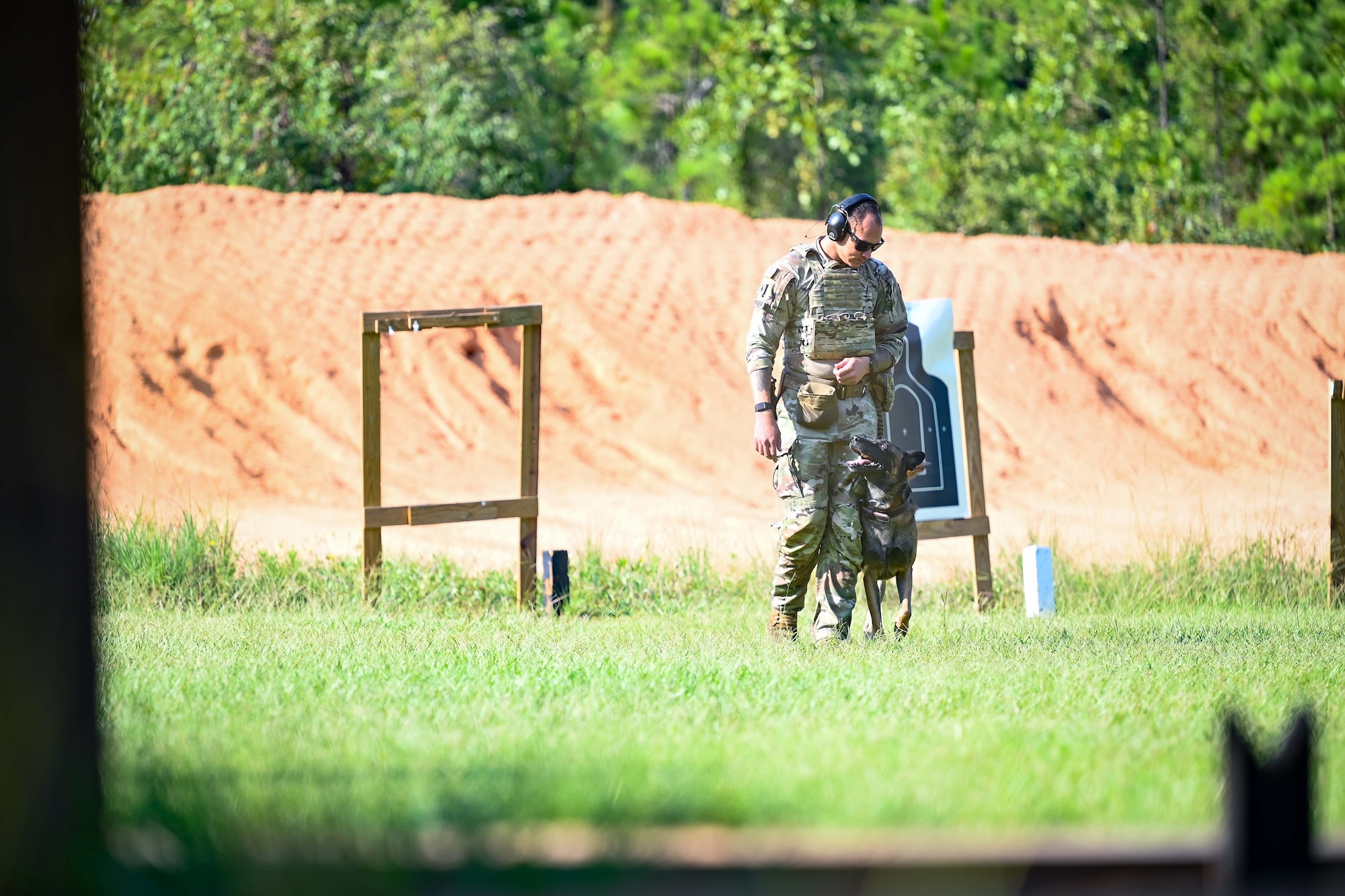 A soldier and his dog walk back together from a firing range.