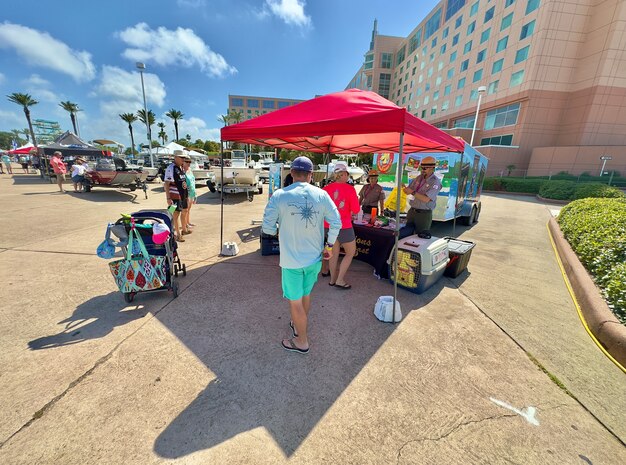 vendor booths and boats are set up at a boat show with a large hotel in the background