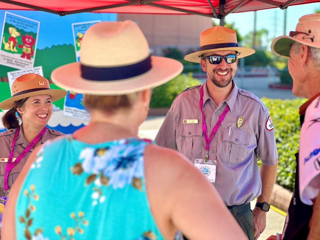 a man and a woman in park ranger uniforms are talking to two people