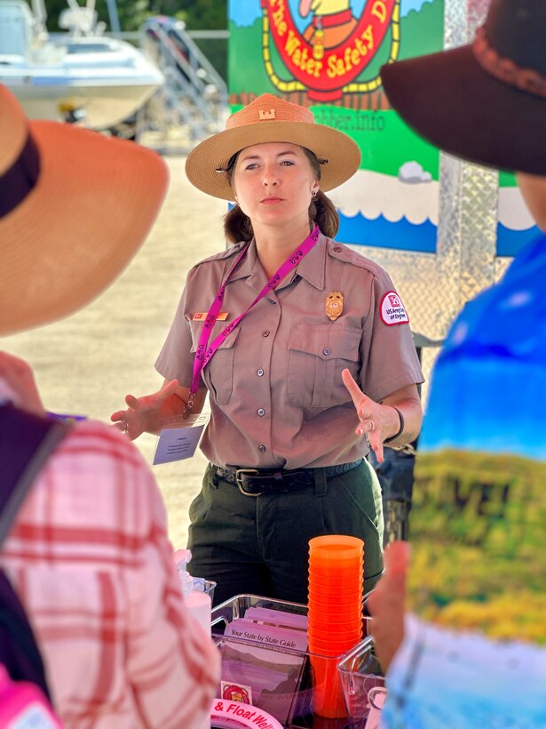 a woman in a park ranger uniform is talking to two people