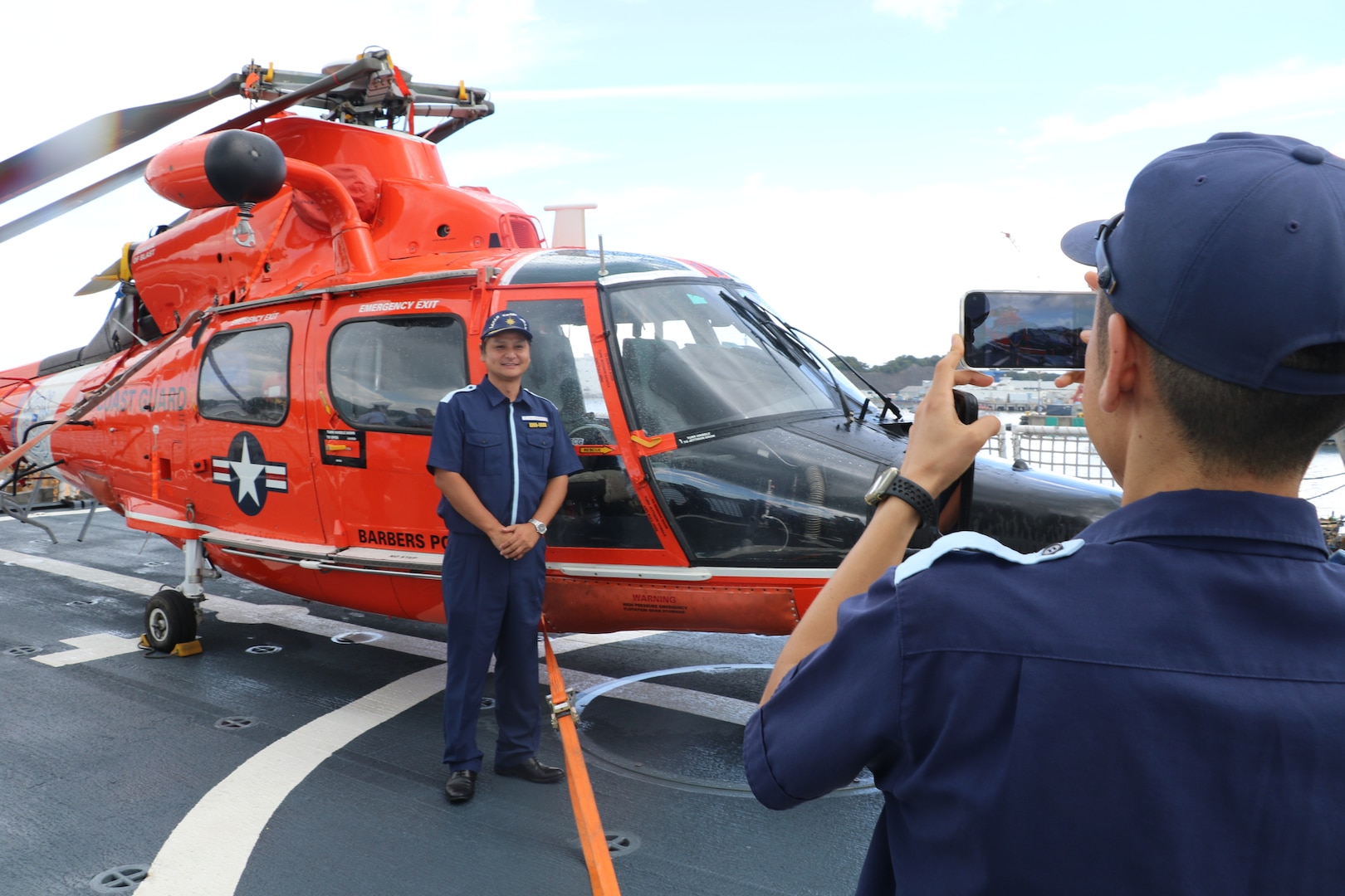 Capt. Tetsuhiro Nakagawa, the Director for International Strategy for the Japan Coast Guard, poses for a photo with a Coast Guard MH-65 Dolphin helicopter after touring the Coast Guard Cutter Munro (WMSL 75) during the cutter’s port call to Yokosuka, Japan, Aug. 8, 2023. Yokosuka was Munro’s first international port call during their months-long deployment to the Indo-Pacific region. (U.S. Coast Guard photo)