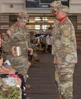 U.S. Army Command Sgt. Maj. Christopher L. Mullinax, the outgoing command sergeant major of the 1st Infantry Division and Fort Riley, places an artillery canister on his seat during a Victory with Honors and relinquishment of responsibility ceremony at King Field House on Fort Riley, Kansas, Aug. 9, 2023. The artillery canister symbolizes the raising of the flag, therefore signifying Mullinax’s last day as the command sergeant major of the 1st Inf. Div. and Fort Riley. (U.S. Army photo by Spc. Dawson Smith)