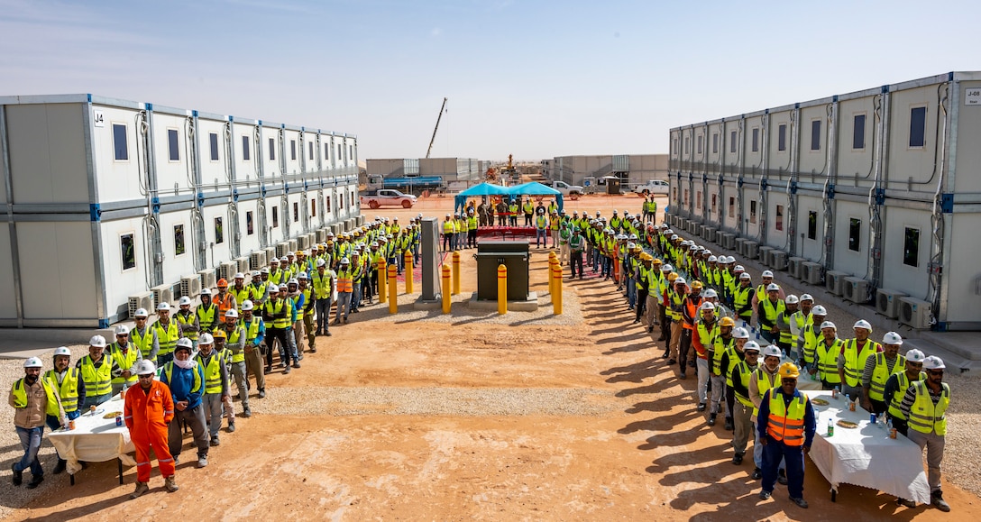 Workers stand around completed housing modules.