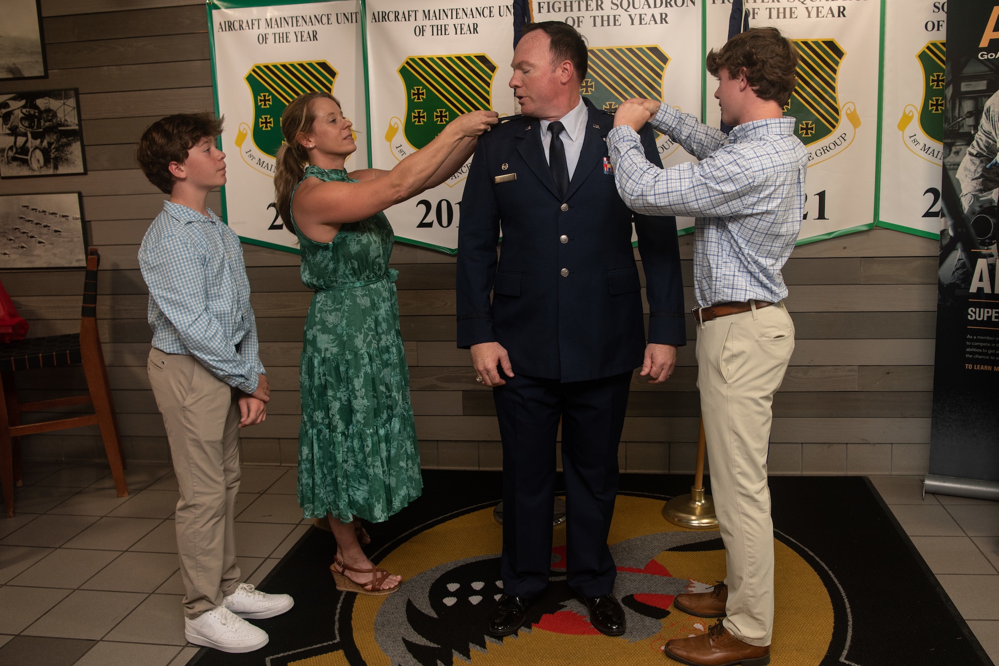 Col. Timothy Strouse stands while his wife and sons pin on his new colonel rank.