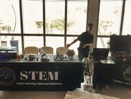 Pearl Harbor Naval Shipyard (PHNSY) Engineer Ryan Saito, from Code 100TO.32 Technology Insertion, gestures to the PHNSY booths that are set up and ready for students to interact with the hands-on demonstrations during a science, technology, engineering, and mathematics (STEM) event at the Pacific Fleet Submarine Museum.