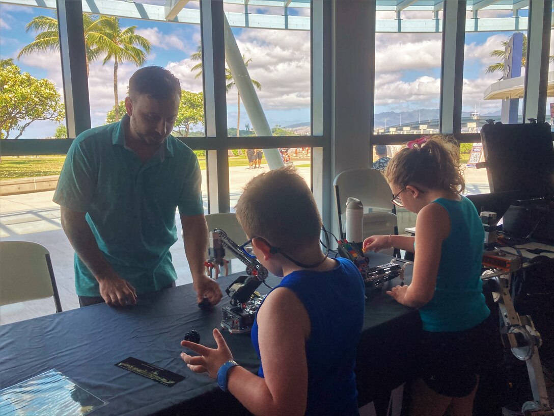 Pearl Harbor Naval Shipyard Analyst Nick Bove, left, from Code 100TO.31 Innovation, demonstrates the STEM educational Lego kits to students during a science, technology, engineering, and mathematics event at the Pacific Fleet Submarine Museum.