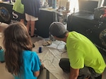 Pearl Harbor Naval Shipyard Engineer Vance Hashimoto, right, from Code 100TO.32 Technology Insertion, demonstrates how to use a robotic arm to students during a STEM event at the Pacific Fleet Submarine Museum