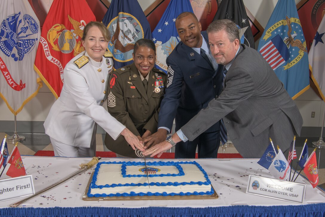 A group of four leaders from The Defense Logistics Agency cut a cake.