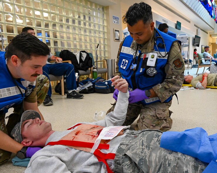 First Responders from the 5th Medical Group bandage a patient during the Ready Eagle exercise at Minot Air Force Base, North Dakota, Aug. 10, 2023. After passing through the decontamination area, patients were transferred to the main lobby of the medical group building for further care. (U.S. Air Force photo by Senior Airman Zachary Wright)