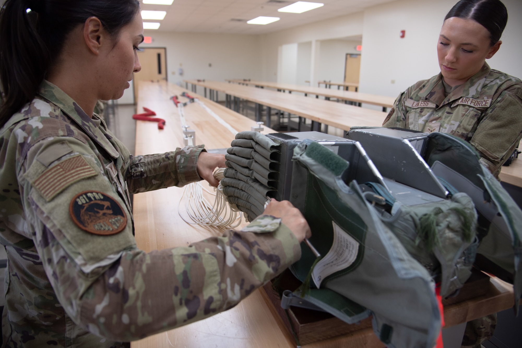 Two Airmen work pack a parachute