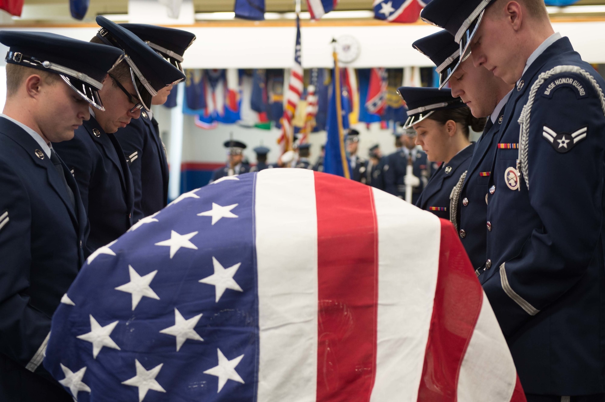 Six Airmen look solemn as they perform duties at a flag-draped coffin