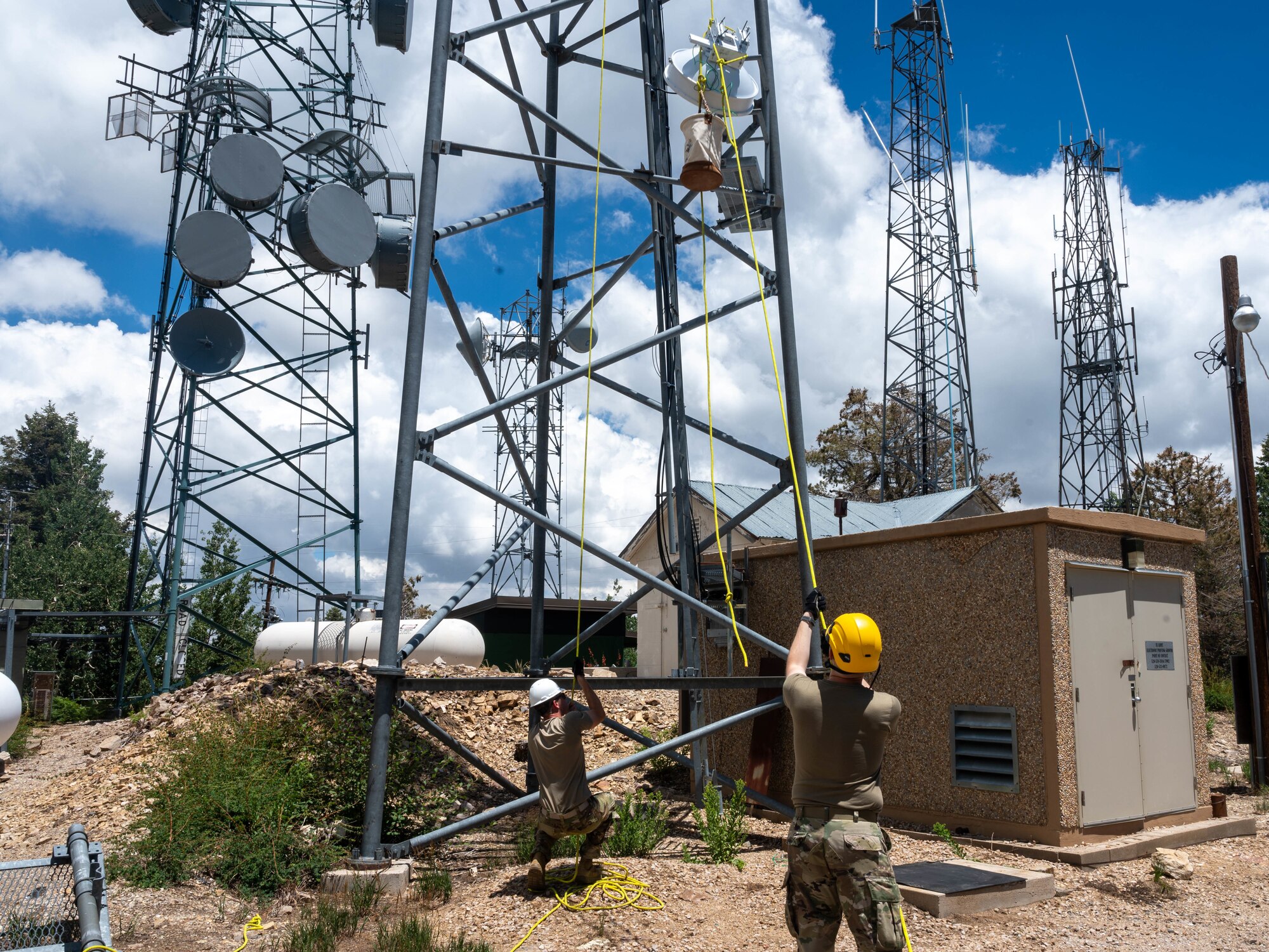 U.S. Air Force 2nd Lt. Warren Jones, 607th Air Control Squadron ground radar systems officer (left), and Airman 1st Class Nash O’Connor, 607th ACS radio frequency transmission systems technician (right), hoist a radio system Aug. 1, 2023, at Mount Lemmon in Tucson, Arizona.