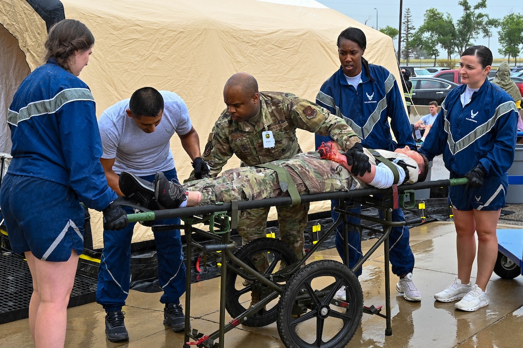 5th Medical Group Patient Decontamination Team first responders transport a patient during Exercise Ready Eagle at Minot Air Force Base, North Dakota, Aug. 10, 2023. The would-be patients were transferred to the decontamination garage and those posing as casualties were treated in the main lobby of the 5th MDG. (U.S. Air Force photo by Senior Airman Zachary Wright)