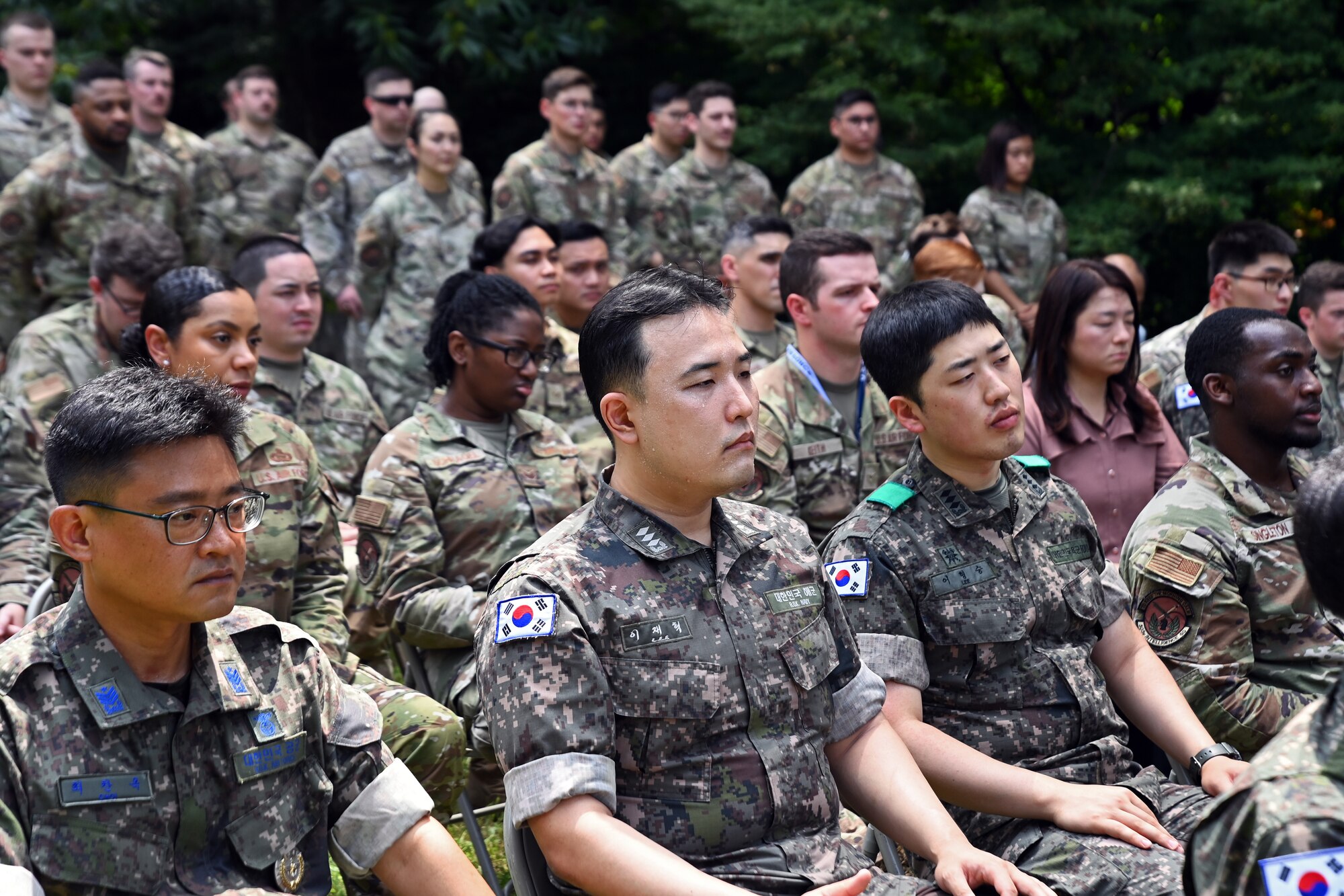 Members of the 303rd Intelligence Squadron and Republic of Korea Air Force listen to remarks from U.S. Air Force Lt. Col. Megan Davis, 303rd IS commander, during a 70th Armistice Anniversary Ceremony at the Hill 180 Memorial Site on Osan Air Base, ROK, Aug. 2, 2023.