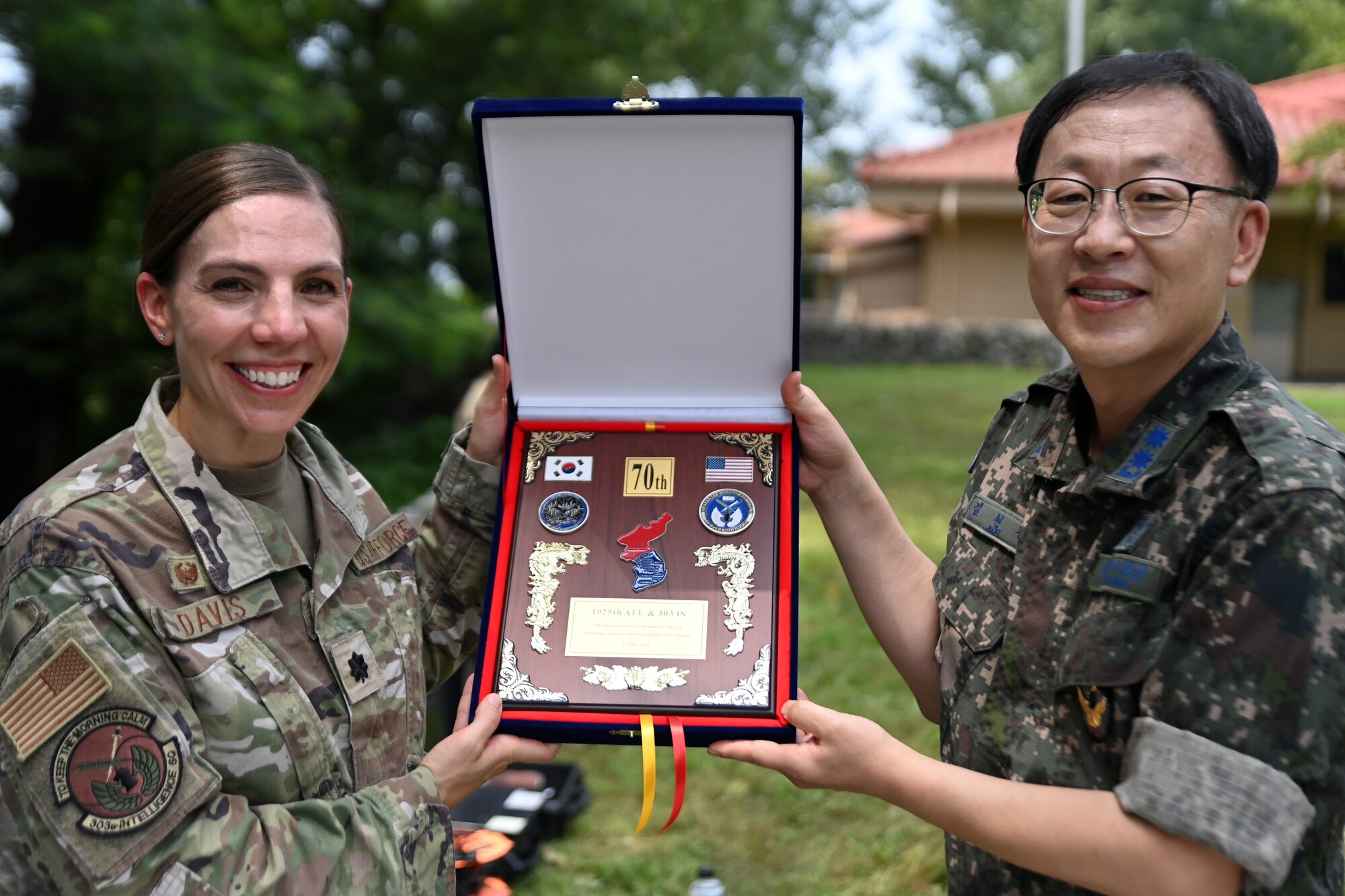 U.S. Air Force Lt. Col. Megan Davis, 303rd Intelligence Squadron commander, left, and Republic of Korea Air Force Lt. Col. Hyun Joo Kim, 1925th Armed Forces Unit commander, hold a commemorative plaque during a 70th Armistice Anniversary Ceremony at the Hill 180 Memorial Site on Osan Air Base, ROK, Aug. 2, 2023.