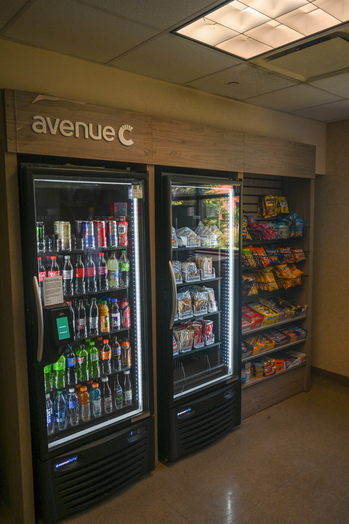 Refrigerators stand next to shelves of snacks.