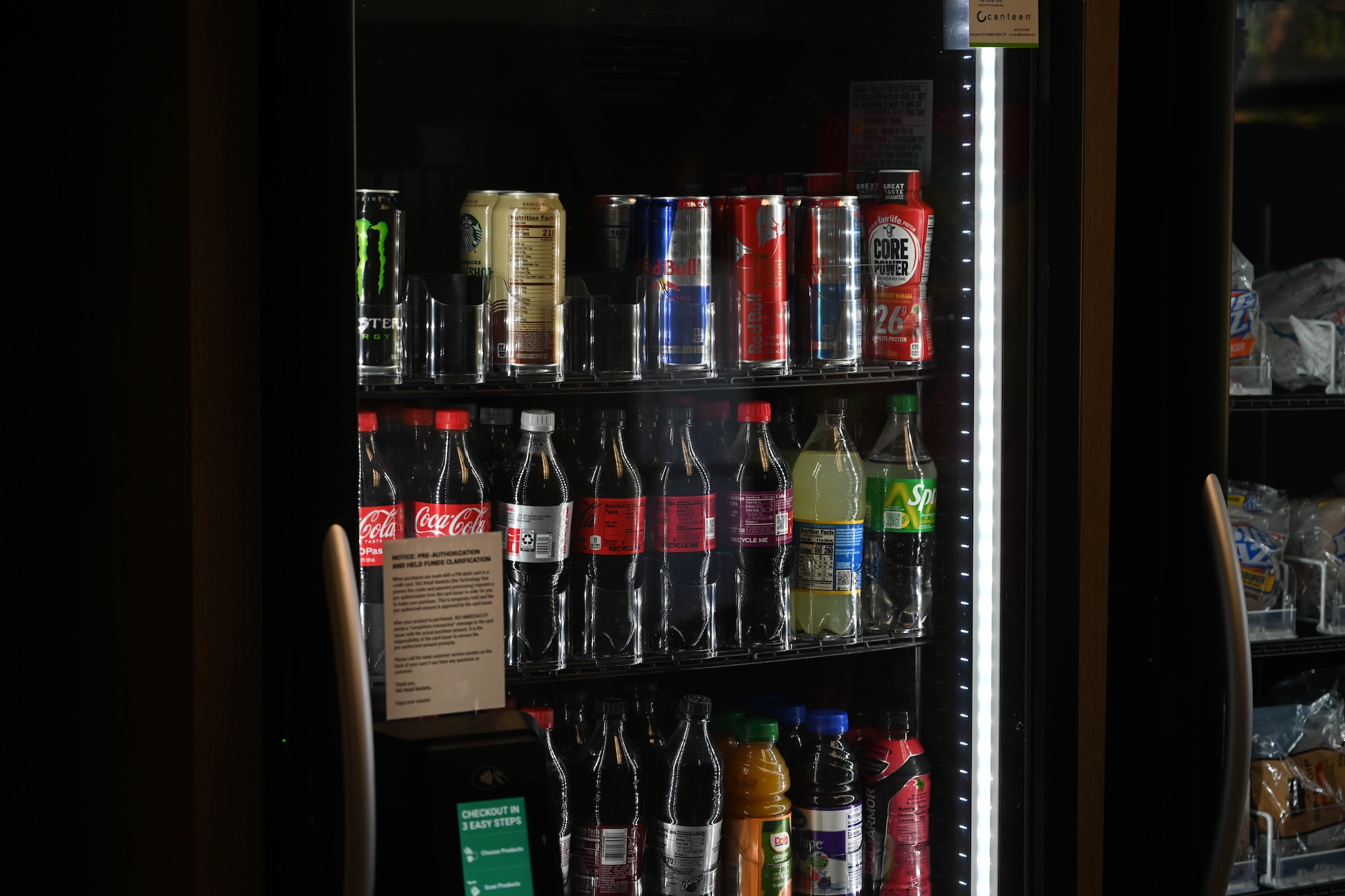 Bottles of drinks are lined up in a refrigerator.