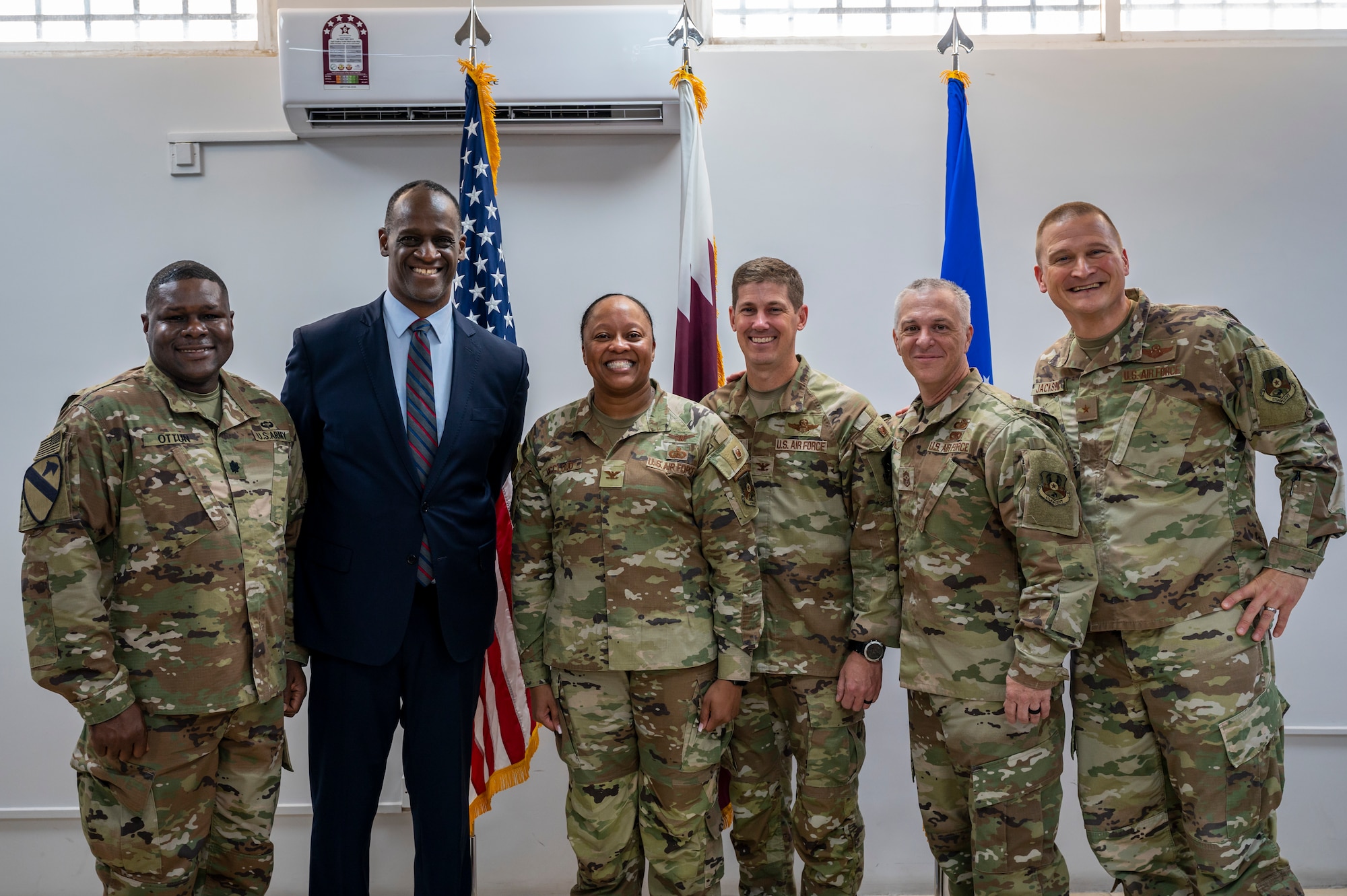 Military members in uniform stand together for a group photo alongside the U.S. Ambassador to Qatar.