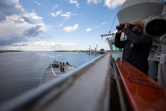 Logistics Specialist 3rd Class Raymond Akintunde, from La Marque, Texas, looks for surface vessels from the bridge of the Arleigh Burke-class guided-missile destroyer USS Roosevelt (DDG 80) as the ship departs Riga, Latvia, Aug. 9, 2023.