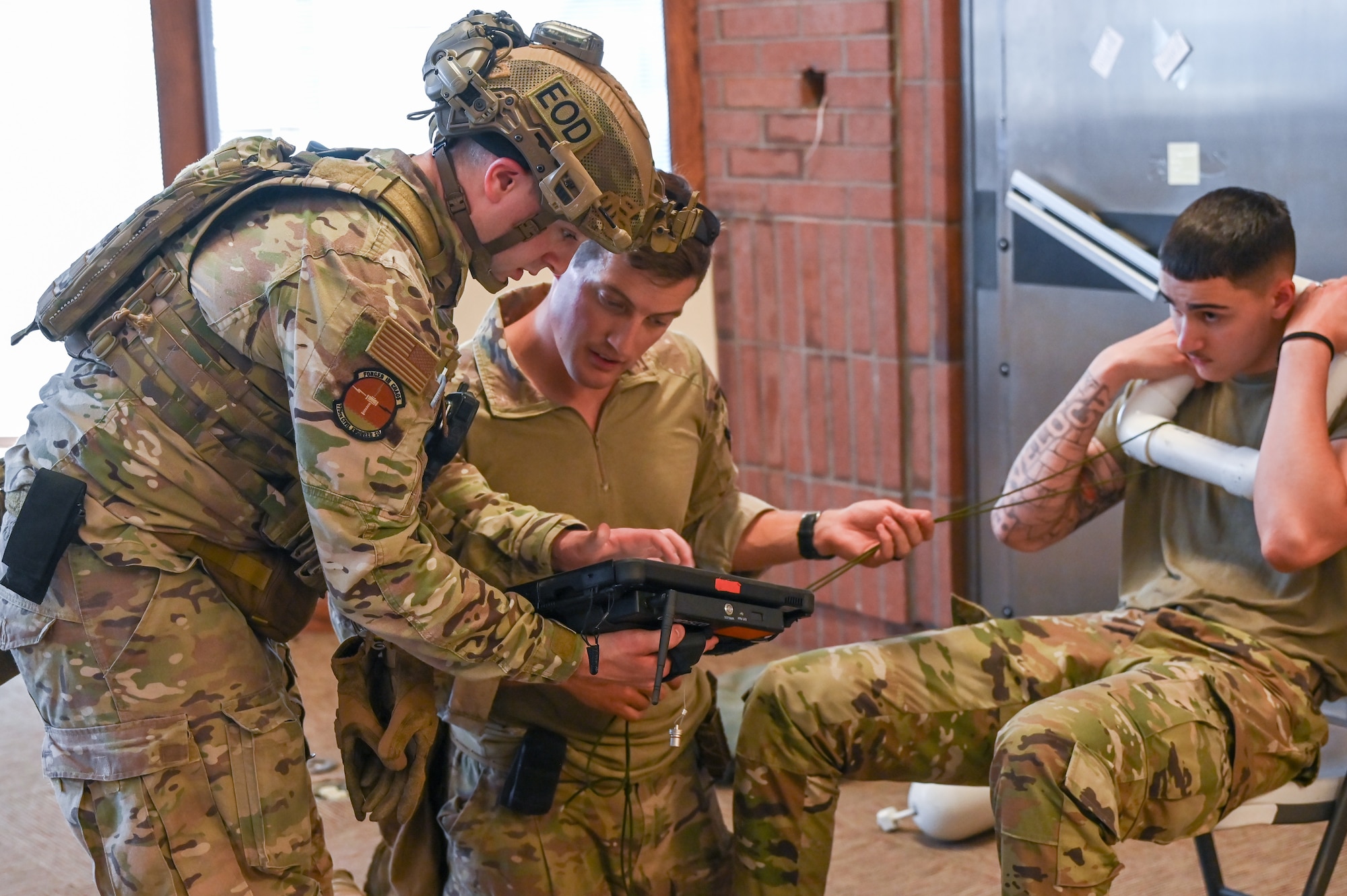 Left, Senior Airman Tanner Randall, 775th Explosive Ordnance Disposal Flight, shows an x-ray of a simulated explosive device to Staff Sgt. Zachary Pennington, 775th EOD Flight, during an off-base training event Aug. 10, 2023, in Roy, Utah.