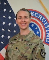Woman wearing army uniform standing in front of US and USAREC flags