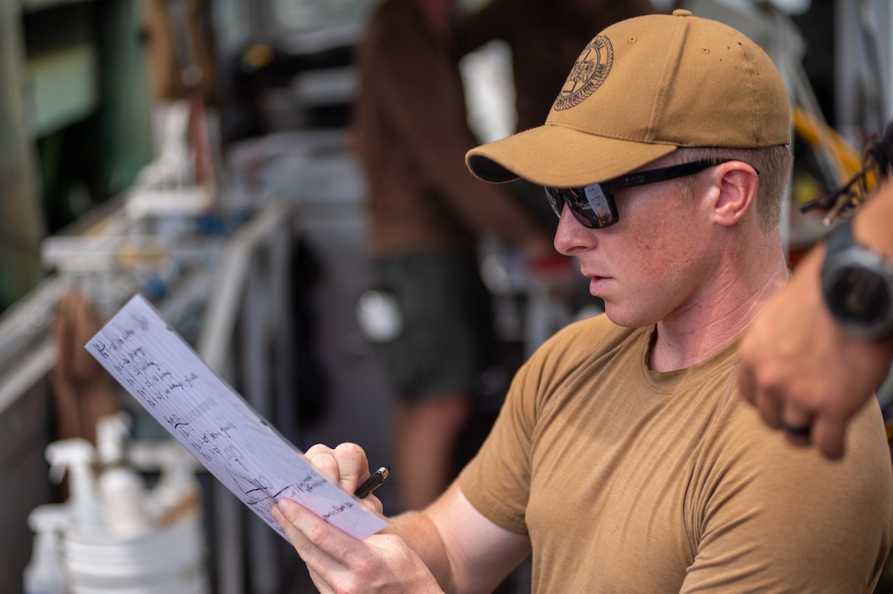 A sailor looks over a piece of paper.