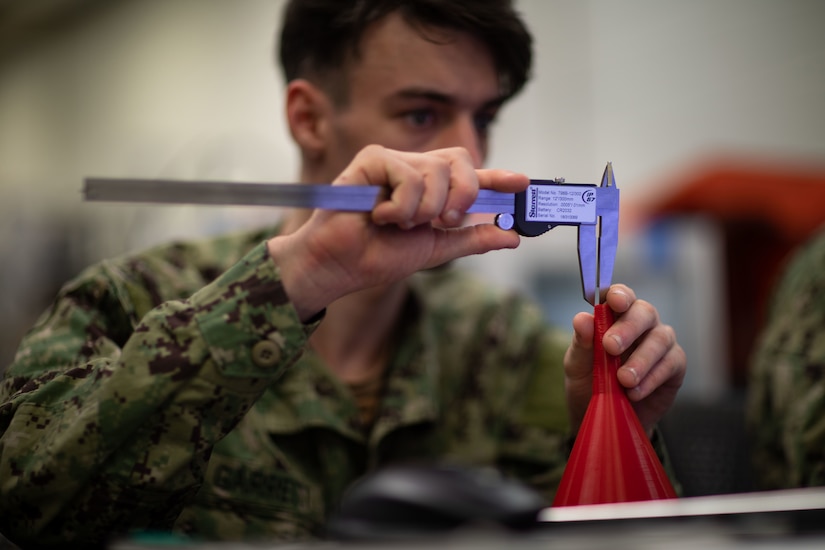 A man in uniform measures a funnel-shaped object.