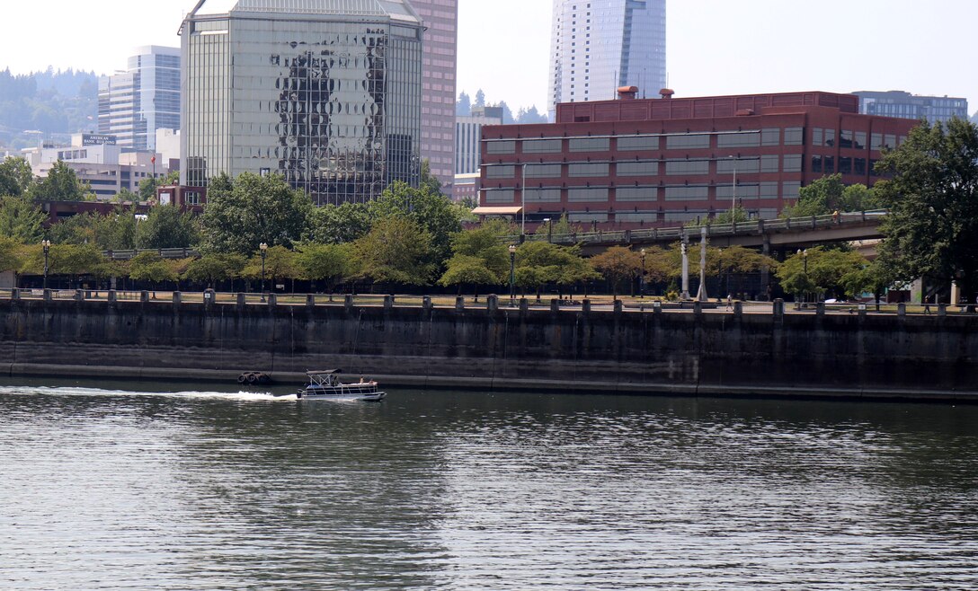 A river with boaters with the City of Portland in the background.