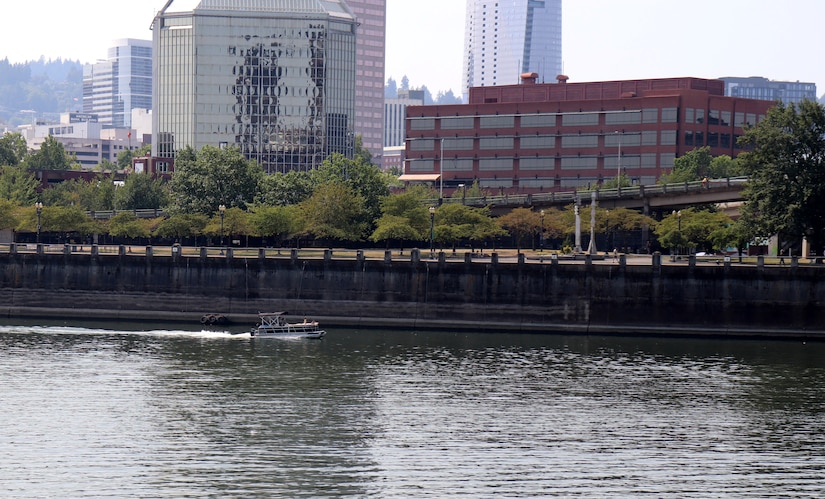 A river with boaters with the City of Portland in the background.