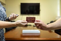 Michelle Wozniak, the III Marine Expeditionary Force Prevention Director, left, gives an emergency service card to Jacob Aimes, the III MEF Inspector General Investigator on Camp Courtney, Okinawa, Japan, August 8, 2023.