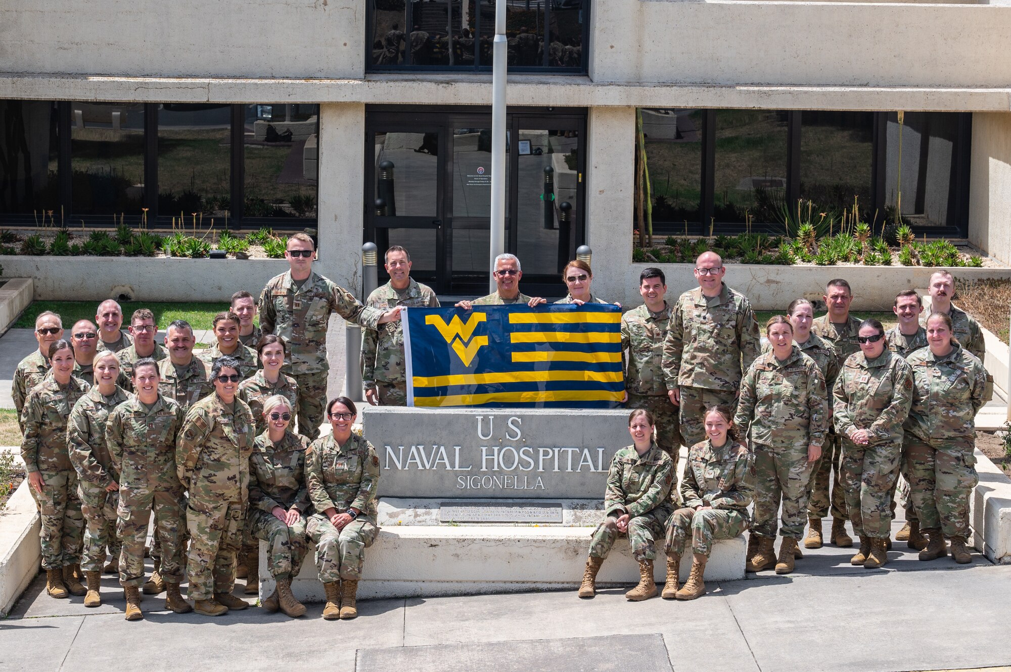 Airmen assigned to the 130th Airlift Wing, McLaughlin Air National Guard Base, W.Va. pose for a group photo in front of the entrance to Naval Air Station Sigonella, Italy’s hospital after completing their Medical Facility Annual Training (MFAT) on July 20, 2023. MFAT allows National Guard medical personnel to receive real-world experience in a military medical facility. (U.S. Air National Guard photo by 2d Lt. De-Juan Haley)
